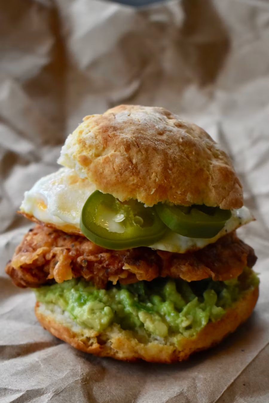 A fried chicken biscuit sandwich with a fried egg and jalapeño.