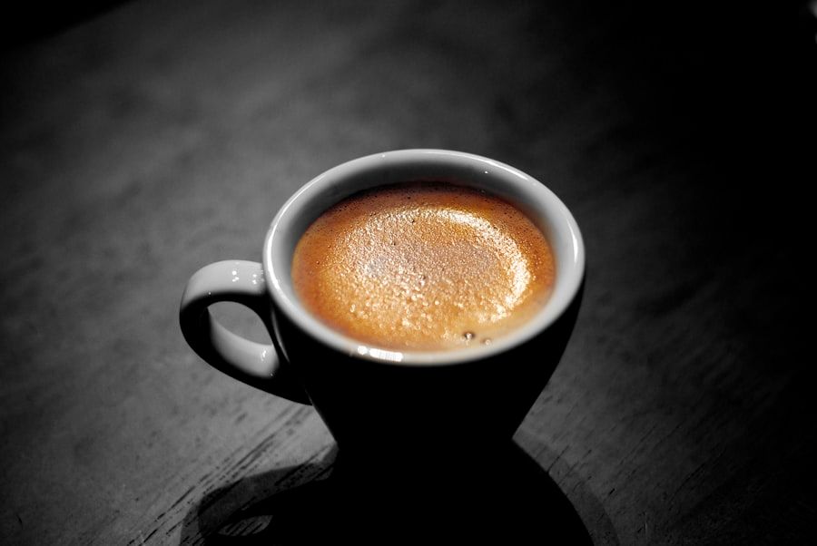 A cortado in a small cup on a dark surface.