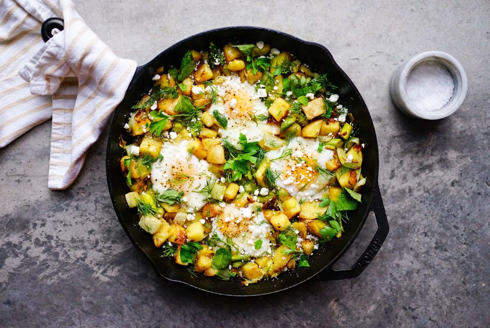 A hot cast-iron skillet of potatoes, eggs, and herbs.