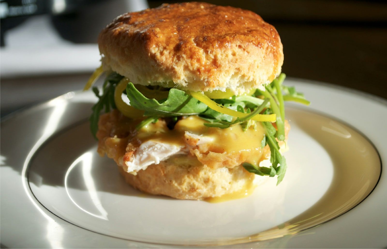 A fried chicken biscuit sandwich with arugula and pickled peppers.